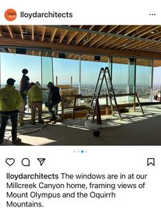 two men are standing in front of windows looking out at the city from inside a building