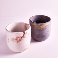 two vases sitting next to each other on a white surface