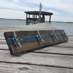 a piece of wood with metal handles on a wooden dock near the water and a pier in the background