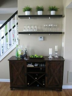 an entertainment center with wine glasses and bottles on the top shelf, next to a staircase