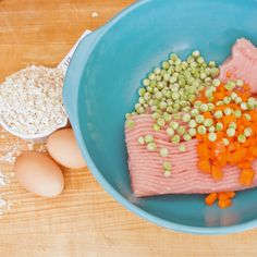 a blue bowl filled with meat and veggies on top of a wooden table