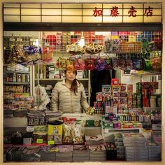 a woman standing in front of a store window filled with food and condiments