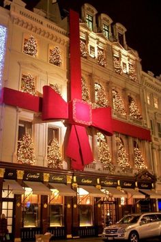 a large red bow on the side of a building with christmas lights in the background