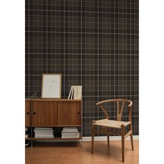 a chair sitting next to a wooden cabinet in front of a wall with black squares on it