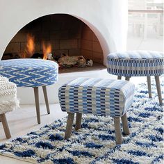 two blue and white stools sitting in front of a fire place next to a rug