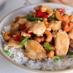 a white plate topped with chicken and cashews on top of rice covered in sauce