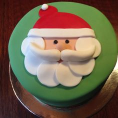 a cake decorated to look like santa claus on a green and silver platter with white frosting