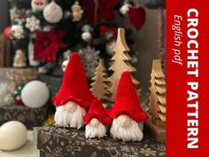 three knitted gnomes sitting on top of a box next to a christmas tree