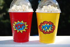 two red and yellow cups with popcorn on them sitting next to each other, one has the word pop written on it