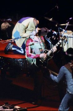 a man with a hat on playing the guitar in front of a group of people