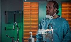 a man in scrubs standing next to a sink