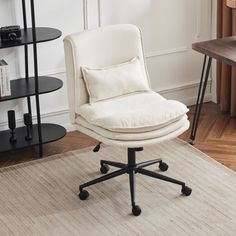 a white chair sitting on top of a wooden floor next to a book shelf filled with books