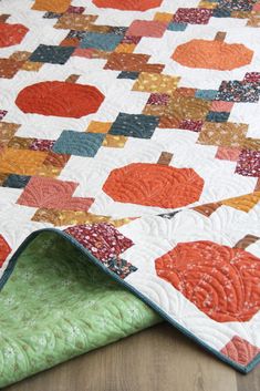 an orange and green quilt on top of a wooden floor