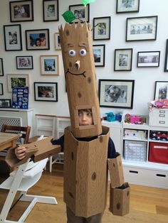 a young boy standing in front of a cardboard tree