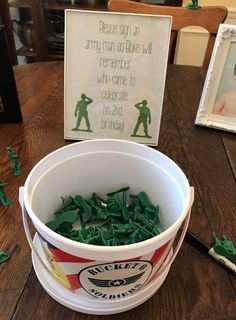 a bucket filled with green candies sitting on top of a wooden table next to a sign