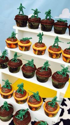 cupcakes with chocolate frosting and green army figurines are on display