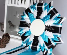 a decorative blue and black bow on top of a white table next to a pine cone