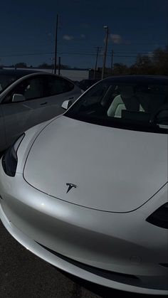 two cars parked side by side next to each other in a parking lot at night