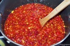 a pot filled with red sauce and a wooden spoon