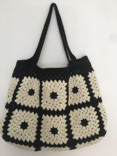 a black and white crocheted bag hanging on a wall