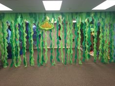 an office cubicle decorated with green streamers and paper decorations on the wall,