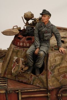 a figurine of a man sitting on top of a tank with other items in the background