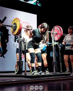 a woman squats on a bench while holding a barbell