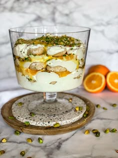 a dessert dish with oranges and pistachio on a marble platter next to it