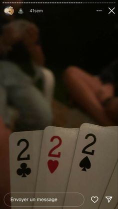 four playing cards sitting on top of each other in front of a man and woman