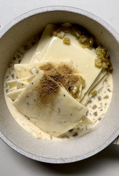 a bowl filled with food on top of a white countertop next to utensils