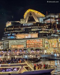 a boat floating on top of a body of water next to a large building at night