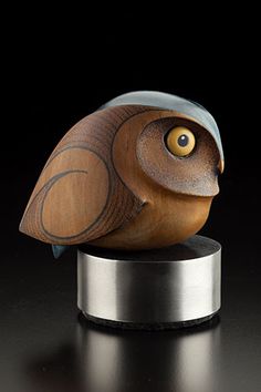 a wooden bird statue sitting on top of a metal stand with an eyeball in it's beak