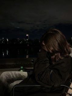 a woman is sitting on a bench looking at her cell phone in the dark night