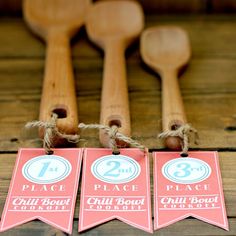 three wooden spoons with tags on them sitting next to some other wood utensils