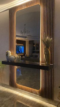 a large mirror sitting on top of a table in front of a wall mounted tv