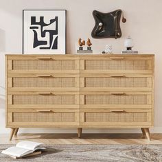 a wooden dresser sitting in a living room next to a painting and an open book