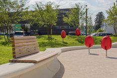 a park bench sitting on top of a brick walkway next to grass and trees with red balls in the background