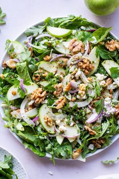 a white plate topped with salad next to an apple