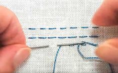 someone is stitching something on the side of a white piece of cloth with blue thread