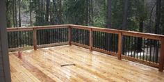 a wooden deck with metal railings surrounded by trees