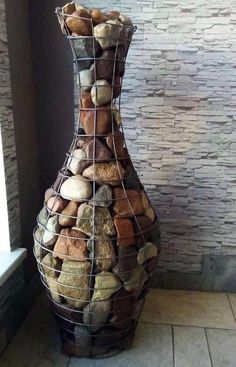 a large vase made out of rocks sitting on the floor next to a brick wall