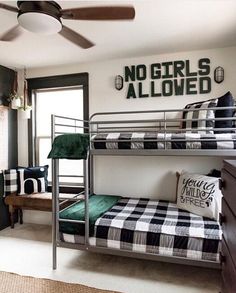 two bunk beds in a room with no girls allowed on the wall above them, and one bed has a black and white checkered blanket