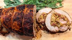 sliced pork with stuffing and green herbs on a cutting board next to some meats