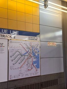 a subway sign is hanging on the wall next to a subway track 2 sign that says blue line