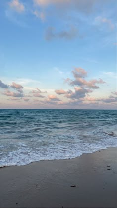 an ocean view with waves crashing on the shore and clouds in the sky above it