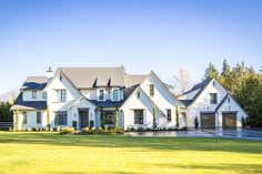 a large white house in the middle of a grassy area with trees and bushes around it