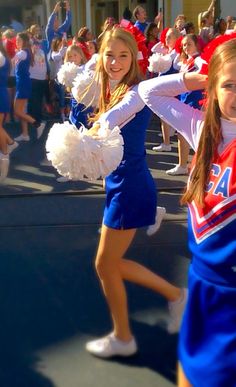 two cheerleaders are dancing in front of a group of other cheerleaders