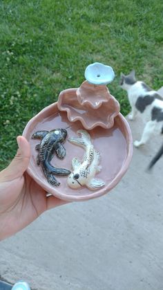 a person holding a tray with small animals in it and a cat walking behind them