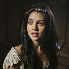 a woman with long black hair wearing a tiara and posing for a photo in the dark