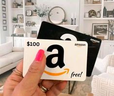 a person holding up a $ 100 amazon gift card in front of a white couch